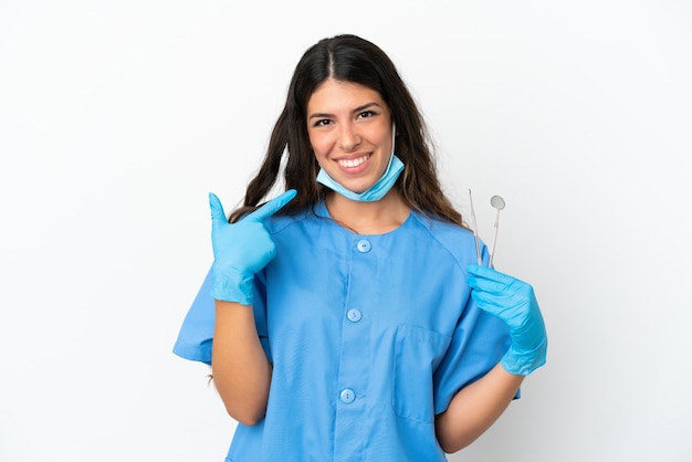 Foto mujer dentista sosteniendo herramientas sobre fondo blanco aislado dando un gesto de pulgar hacia arriba