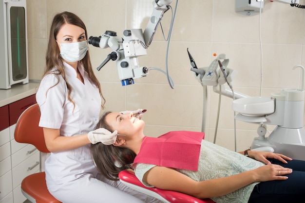 Mujer dentista en su oficina tratando a paciente femenino