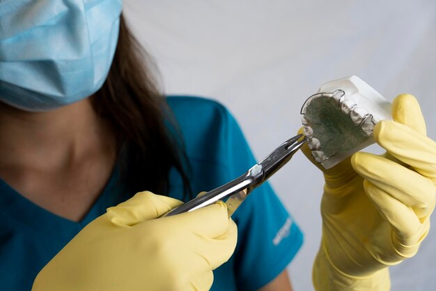 Foto la mujer dentista tiene dentaduras postizas en sus manos e instrumentos.