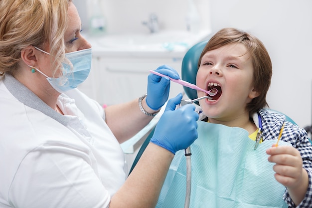 Mujer dentista trabajando en su clínica tratando los dientes del joven