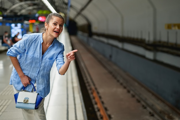 Foto mujer dentro del metro esperando en el andén de una estación de tren para que llegue el tren.