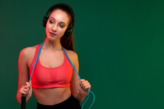 Mujer de deporte atractivo con saltar la cuerda y mujer fuerte escuchar música en auriculares en el interior