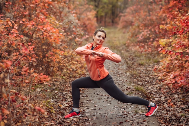 Mujer de deporte cansada en ropa deportiva en el bosque de otoño