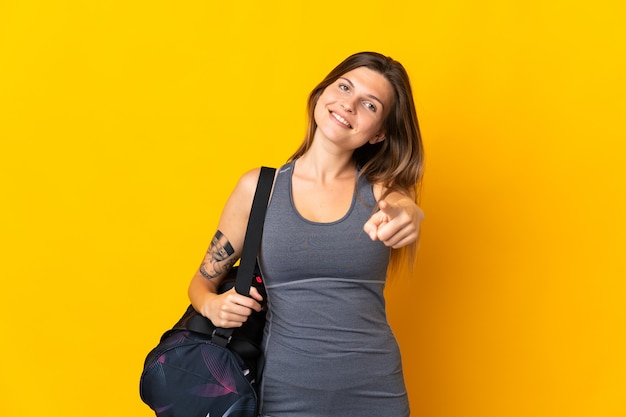 Mujer de deporte eslovaco con bolsa de deporte aislada en la pared amarilla apuntando al frente con expresión feliz