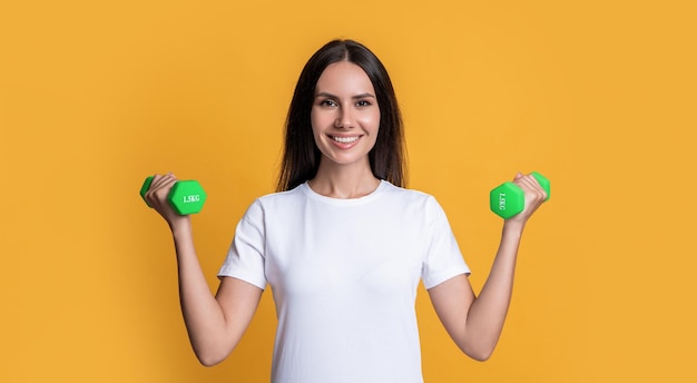 Mujer de deporte feliz con mancuernas de fitness aislado sobre fondo amarillo