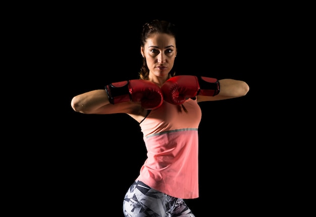 Mujer del deporte en fondo oscuro con los guantes de boxeo