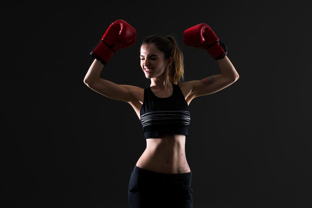 Mujer del deporte con los guantes de boxeo en fondo oscuro