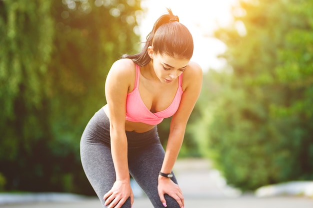 La mujer del deporte se relaja en el fondo del sol