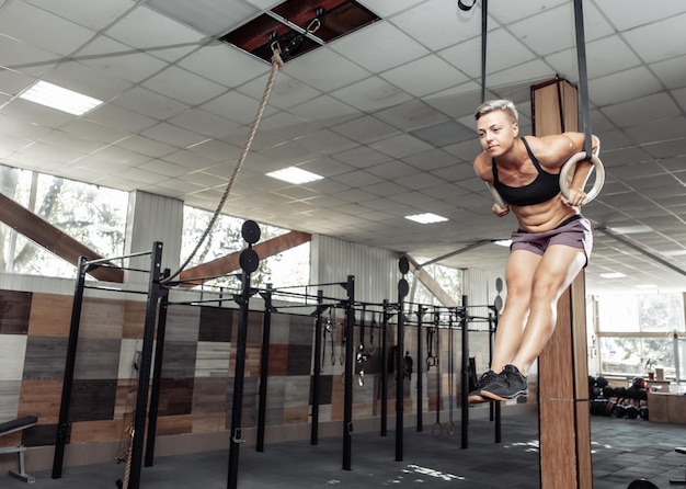 Foto mujer deportista atlética haciendo ejercicio con anillos de gimnasia en un moderno gimnasio cruzado