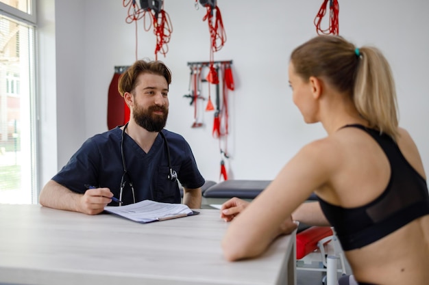 Mujer deportista en una consulta con un médico fisioterapeuta en una clínica de rehabilitación