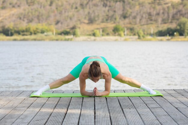 Foto mujer deportista estirando los músculos en un parque frente al lago mujer atlética estirando