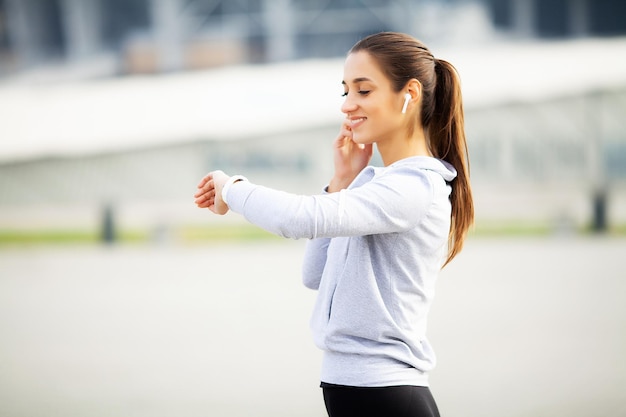 Mujer deportista haciendo ejercicios y escuchando música en el entorno urbano.