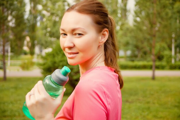 Mujer deportiva activa que sostiene la botella después del entrenamiento