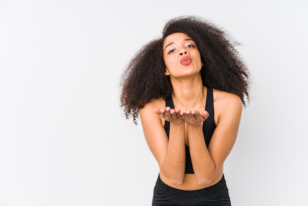 Mujer deportiva afroamericana joven que dobla los labios y que sostiene las palmas para enviar beso del aire.