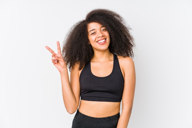 Mujer deportiva afroamericana joven que muestra la muestra de la victoria y que sonríe ampliamente.