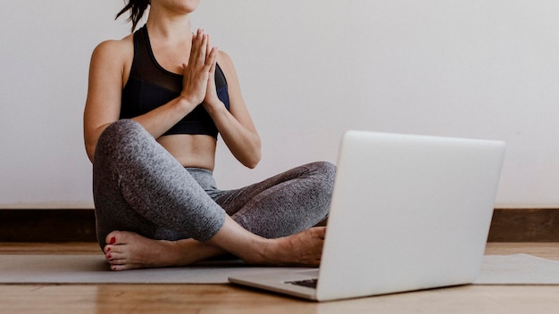 Mujer deportiva aprendiendo yoga en línea a través de una computadora portátil