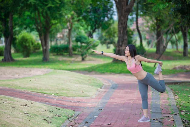 Mujer deportiva asiática estirando el cuerpo respirando aire fresco en el parque Gente de Tailandia Concepto de fitness y ejercicio