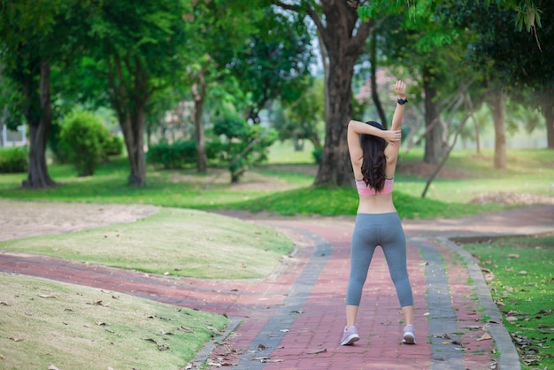 Mujer deportiva asiática estirando el cuerpo respirando aire fresco en el parque Gente de Tailandia Concepto de fitness y ejercicio