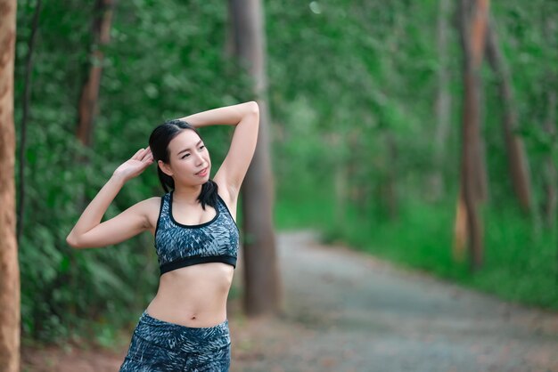 Mujer deportiva asiática estirando el cuerpo respirando aire fresco en el parqueGente tailandesaConcepto de fitness y ejercicioJogging en el parqueCuerpo de calentamiento