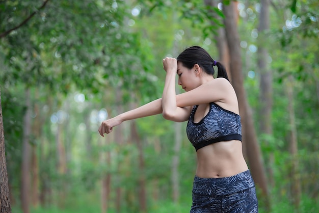 Mujer deportiva asiática estirando el cuerpo respirando aire fresco en el parqueGente de TailandiaConcepto de fitness y ejercicioJogging en el parqueCuerpo de calentamientoSiéntate para zapatos con cordones