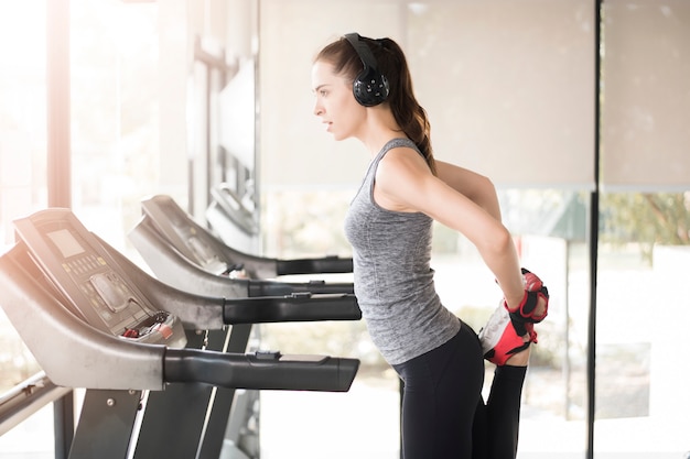 La mujer deportiva bastante joven es calentamiento en gimnasio, forma de vida sana