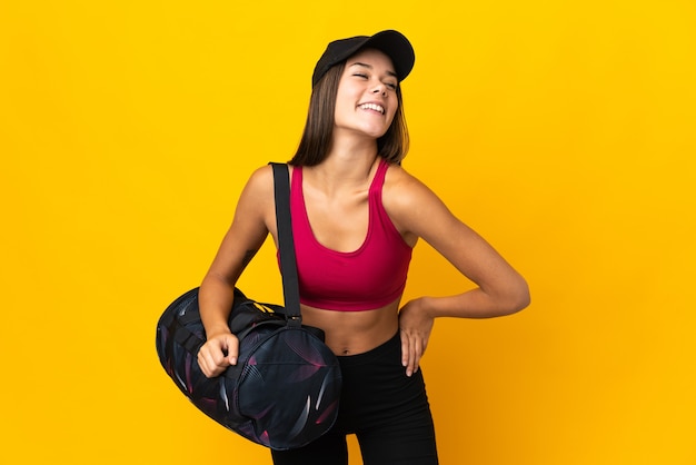 Mujer deportiva con bolsa de deporte posando con los brazos en la cadera y sonriendo