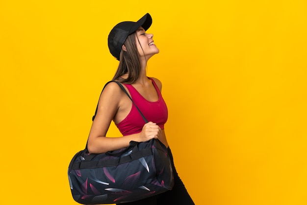 Mujer deportiva con bolsa de deporte riendo en posición lateral