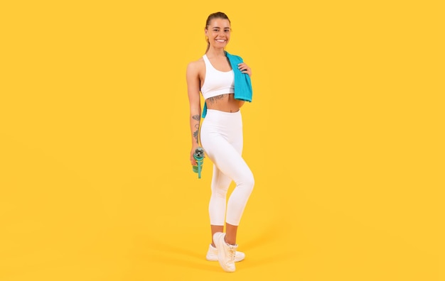 Mujer deportiva con botella de agua sobre fondo amarillo