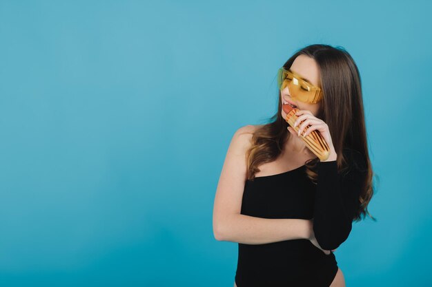 mujer deportiva comiendo hot dog con fondo azul