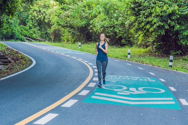 Mujer deportiva corriendo en la carretera al amanecer. Concepto de bienestar fitness y entrenamiento