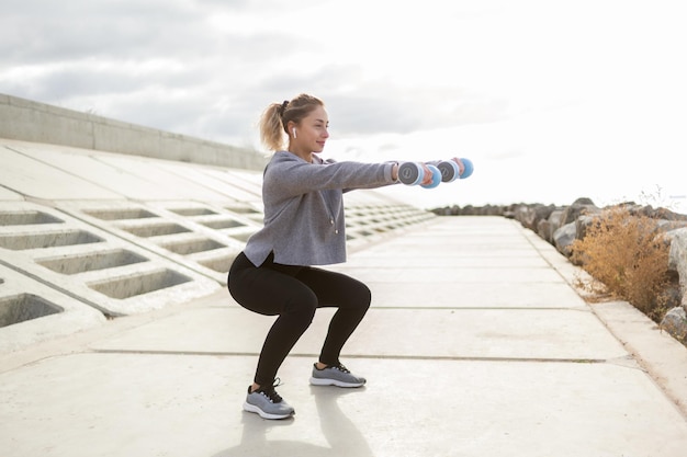 Una mujer deportiva delgada entrena los músculos de las piernas con pesas al aire libre Estilo de vida saludable Fitness culturismo