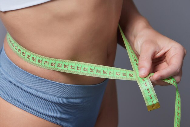 Una mujer deportiva a dieta muestra cuánto peso ha perdido