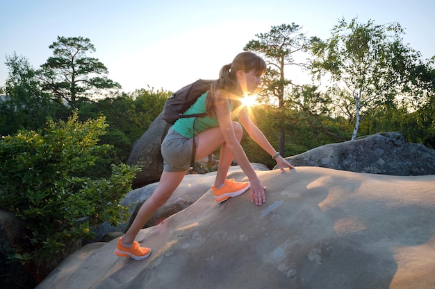 Mujer deportiva escalando sola en el sendero rocoso de la ladera Excursionista femenina superando un acantilado difícil en el camino del desierto Concepto de estilo de vida activo