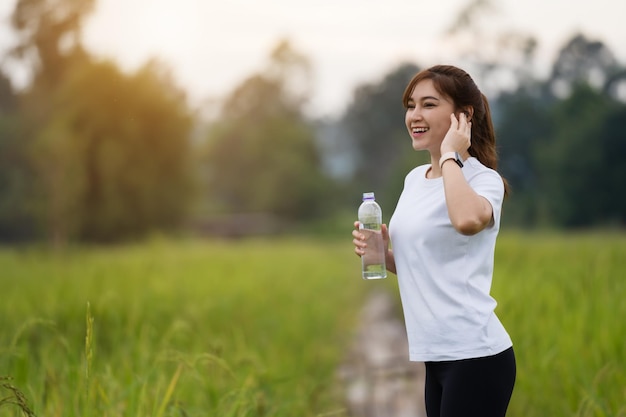 Mujer deportiva escuchando música después de correr en el campo