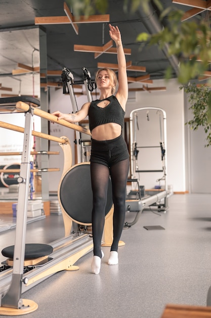 Mujer deportiva está haciendo ejercicios de estiramiento en estudio moderno