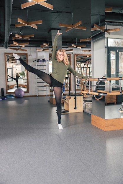 Mujer deportiva está haciendo ejercicios de estiramiento en estudio moderno