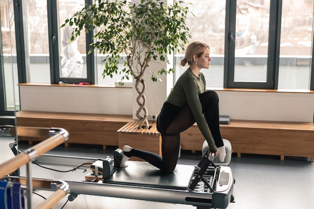 Mujer deportiva está haciendo ejercicios de estiramiento en estudio moderno