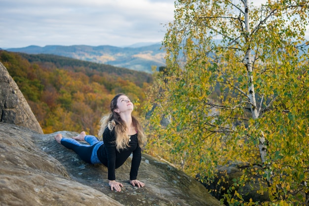 La mujer deportiva está practicando yoga en la cima de la montaña.