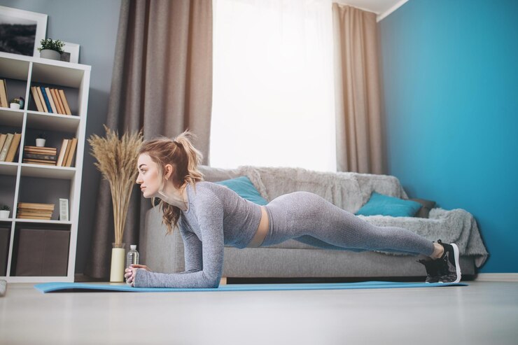 Mujer deportiva haciendo ejercicio de tablones en estera de yoga