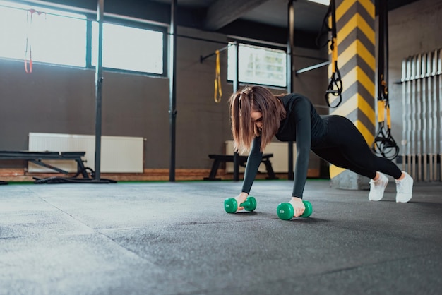 Mujer deportiva haciendo ejercicios con pesas en el gimnasio.