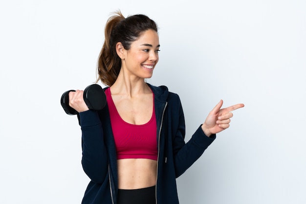 Foto mujer deportiva haciendo levantamiento de pesas sobre blanco aislado apuntando hacia un lado para presentar un producto