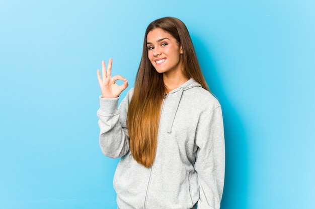 Mujer deportiva joven alegre y confidente que muestra gesto aceptable.