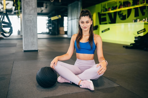 Mujer deportiva joven que mira a la cámara en el gimnasio