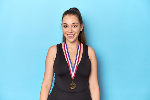 Mujer deportiva con una medalla de oro sobre un fondo de estudio azul