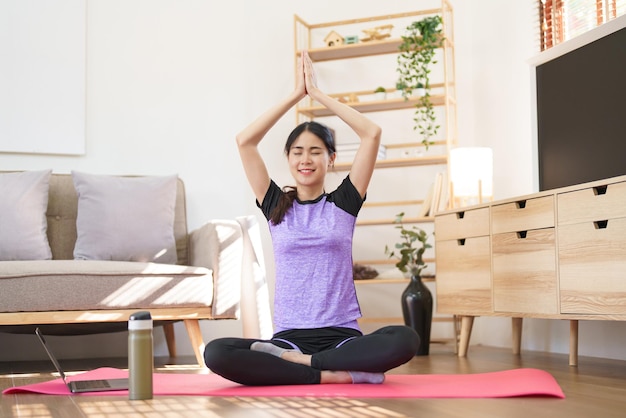 Mujer deportiva meditando para practicar ejercicio de yoga mientras levanta las manos para hacer yoga con pose de namaste