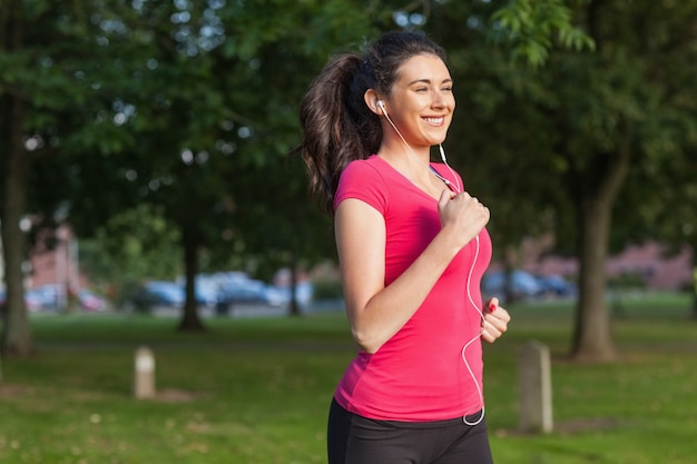 Mujer deportiva motivada que se ejecuta en un parque