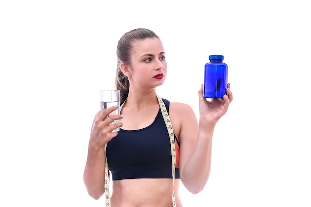 Mujer deportiva con pastillas y botella aislado en blanco