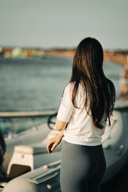 Mujer deportiva en polainas grises de pie en la playa de vuelta a la cámara Chica joven vestida en la playa durante las vacaciones de verano Horizonte de la costa con cometas volando en el fondo