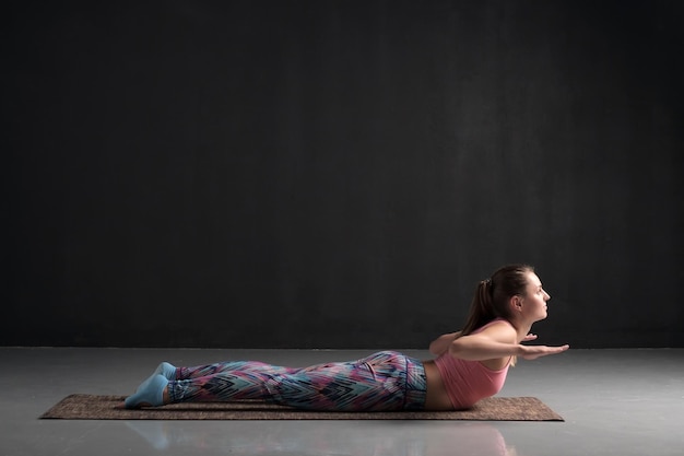 Mujer deportiva practicando yoga haciendo variación de pose de Salabhasana