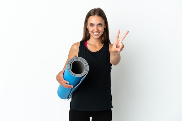 Mujer deportiva que va a clases de yoga mientras sostiene una estera aislada